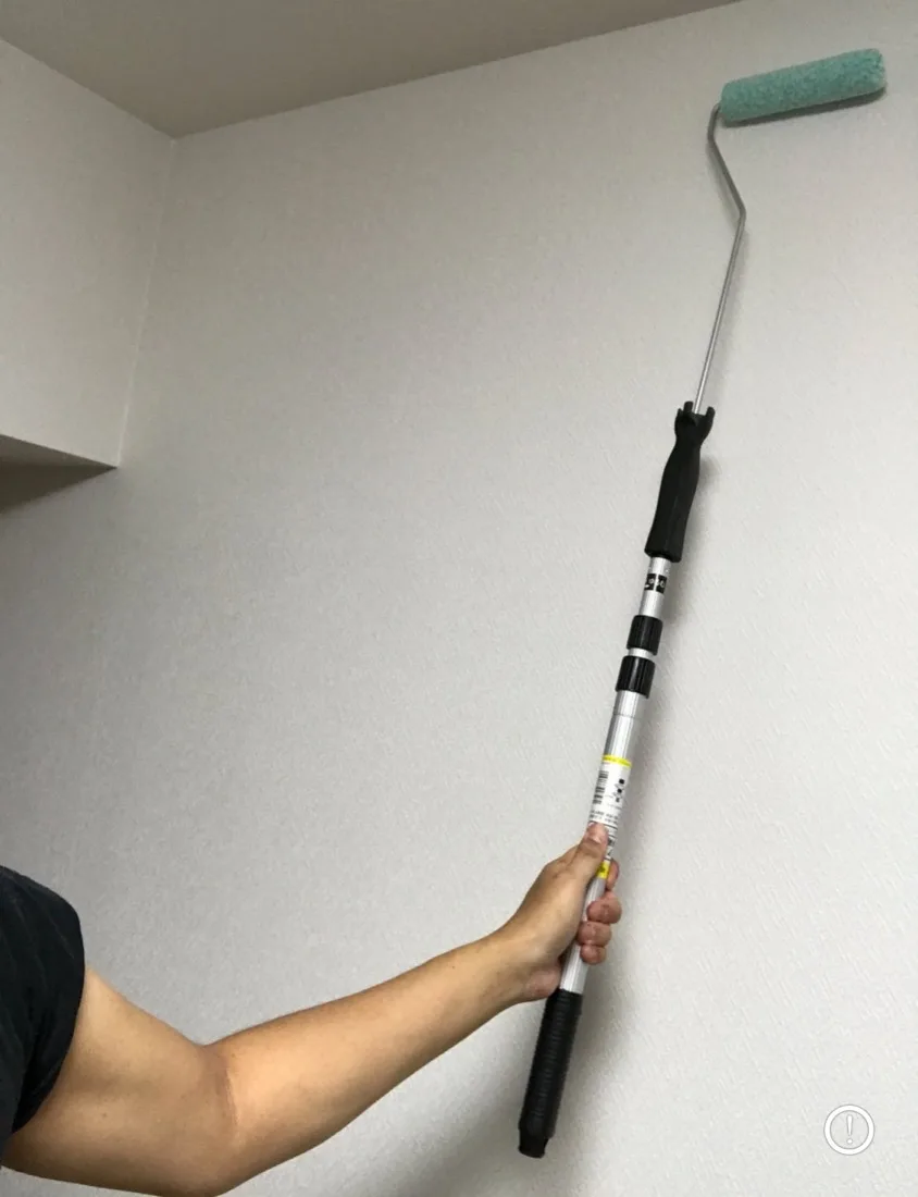 壁紙塗装DIYの準備。自宅で延長ポール付きローラーを持ち上げてシミュレーションしている様子