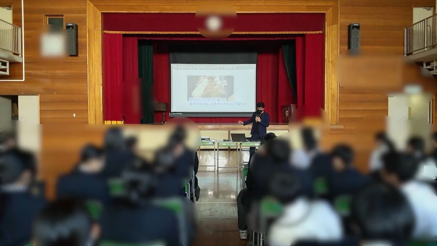 東京都内の中学校の体育館で、生徒たちに向けて職業人講演を行う様子
